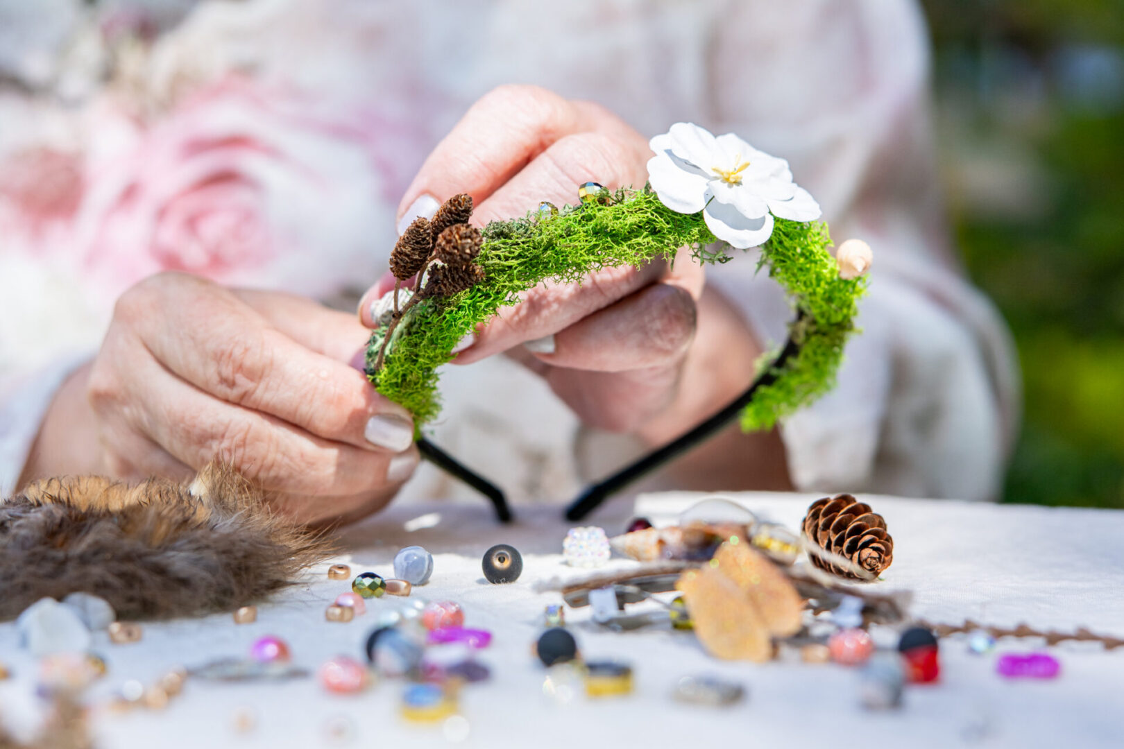 Hands crafting moss-covered floral headband