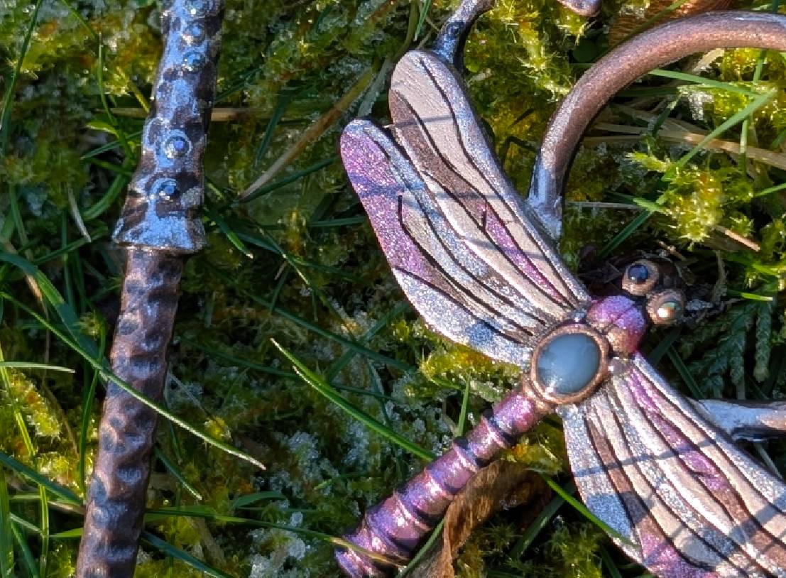 Iridescent purple metal dragonfly ornament on moss