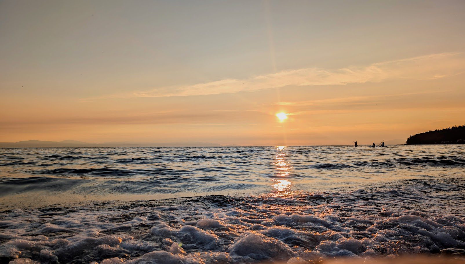 Sunset ocean waves with silhouetted kayakers